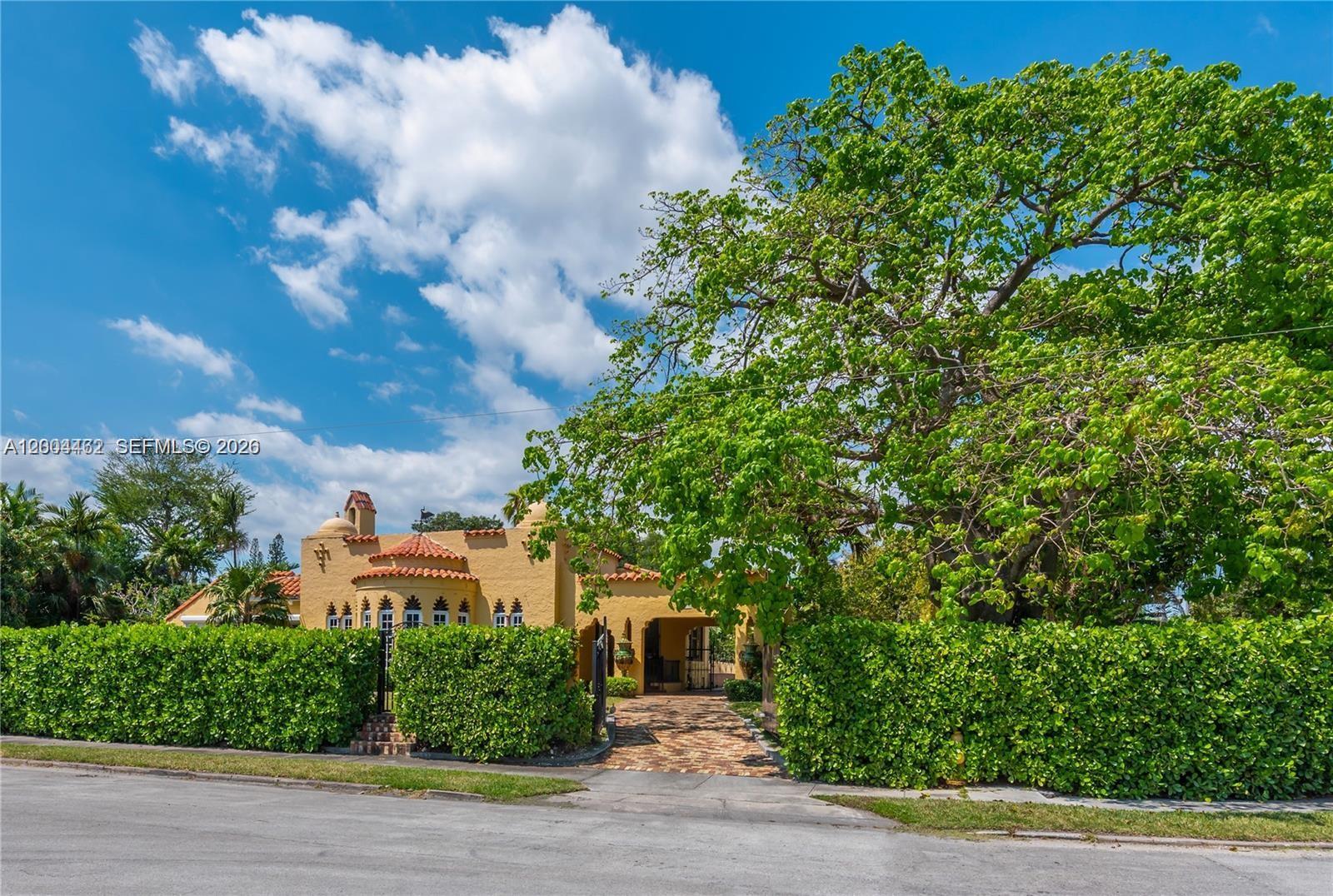 A yellow stucco house with a tiled roof is partially obscured by a large tree — 1036 NE 89th St, Miami FL 33138, MIAMI, FL