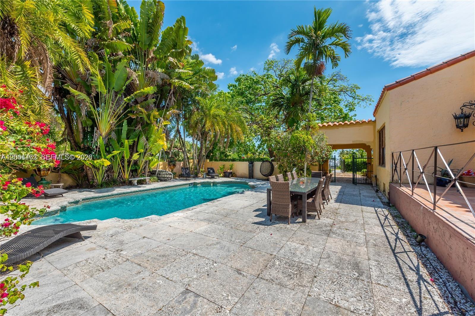 A swimming pool sits on a stone patio next to a house and tropical landscaping — 1036 NE 89th St, Miami FL 33138, MIAMI, FL