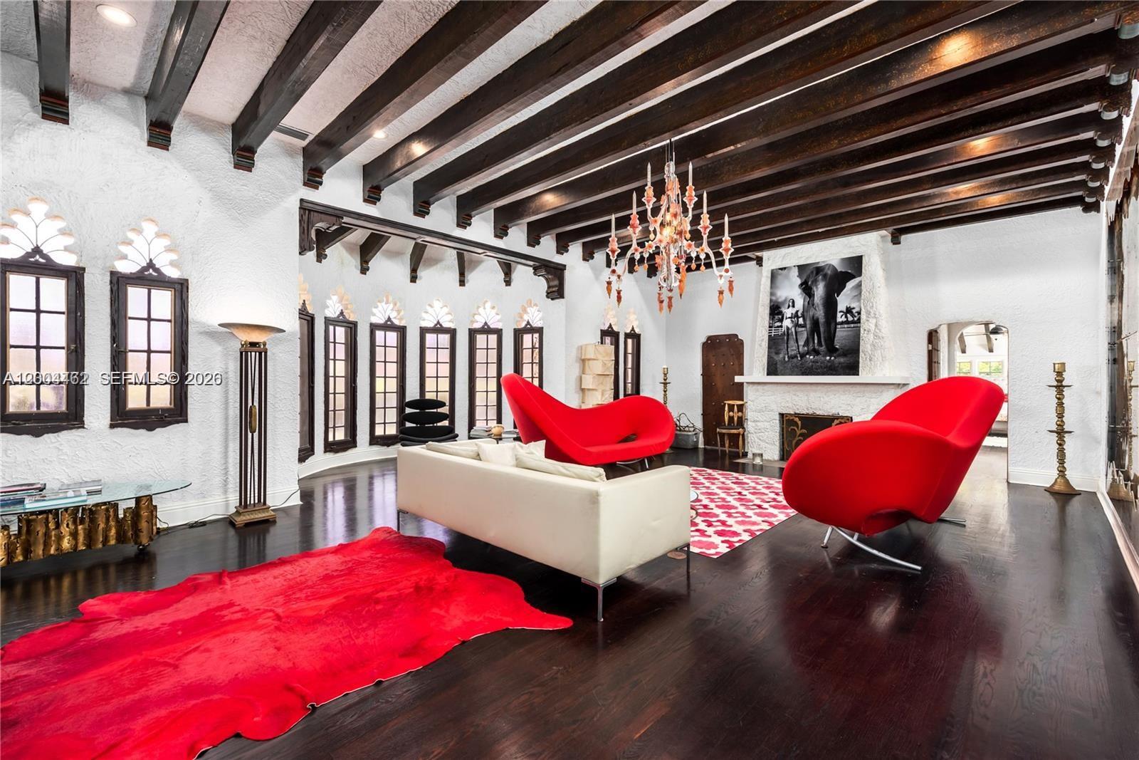 A living room features dark wood ceiling beams, white textured walls, and red accent furniture — 1036 NE 89th St, Miami FL 33138, MIAMI, FL
