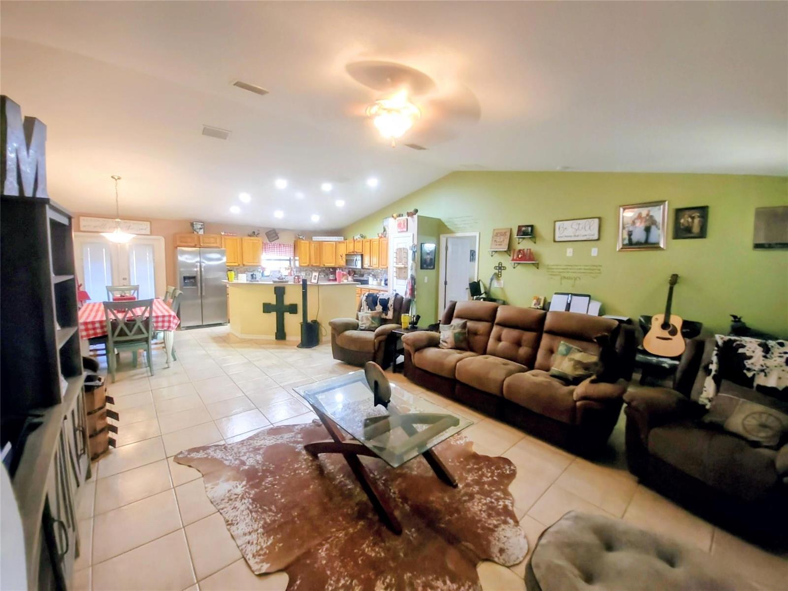 A spacious open-concept living room and kitchen featuring tile floors, brown furniture, and green walls — 1153 Jerdik Drive, Moore Haven FL 33471, MOORE HAVEN, FL