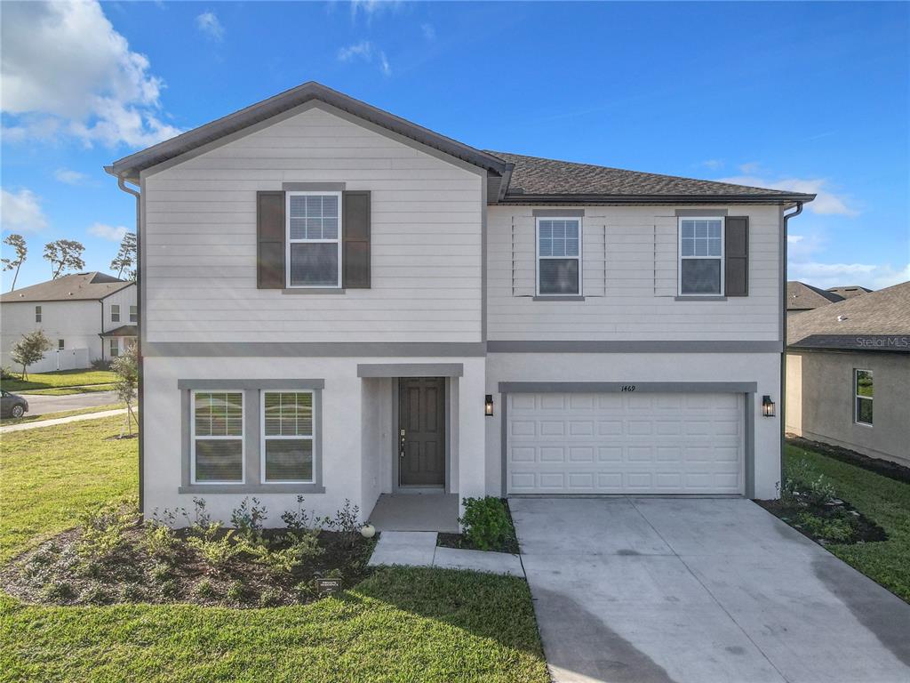 A two-story house features a white stucco and siding exterior with a two-car garage — 1469 ARBOR HILL DRIVE, DELTONA, FL