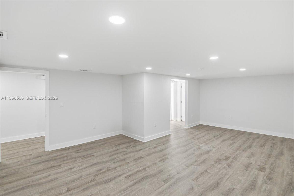 An empty room features light gray walls, recessed lighting, and wood-look flooring — 150 NW 29th St # 160, Miami FL 33127, MIAMI, FL