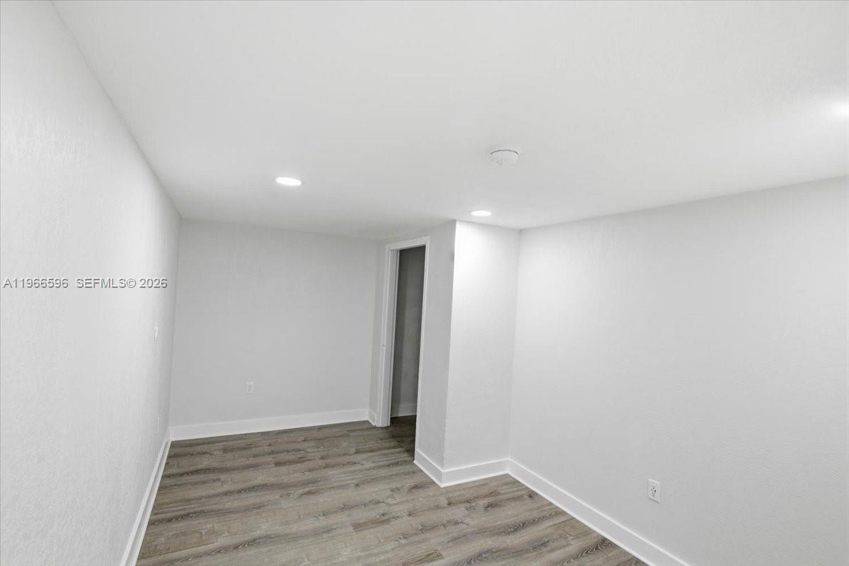A small, empty room features light gray walls, recessed lighting, and wood-look flooring — 150 NW 29th St # 160, Miami FL 33127, MIAMI, FL