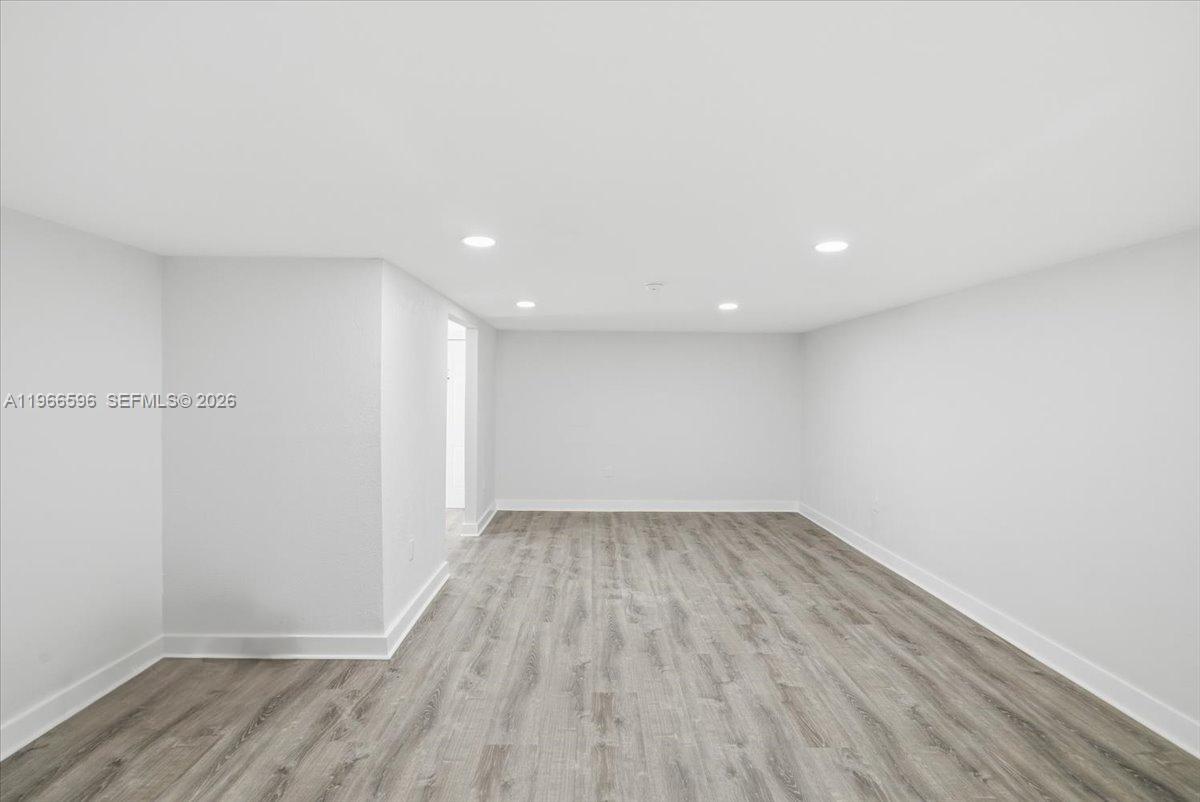 An empty room features light gray walls, recessed lighting, and wood-look flooring — 150 NW 29th St # 160, Miami FL 33127, MIAMI, FL