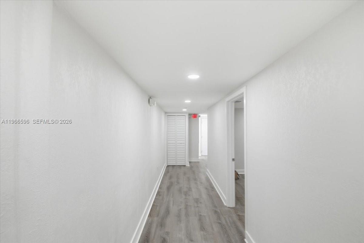 A narrow hallway features white walls, recessed ceiling lights, and gray wood-look flooring — 150 NW 29th St # 160, Miami FL 33127, MIAMI, FL
