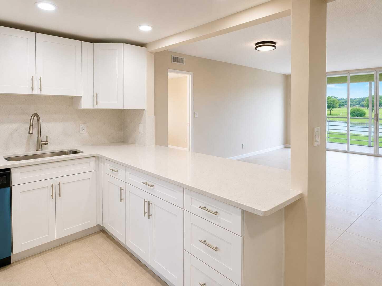 A kitchen with white cabinets and quartz countertops overlooks a living area with balcony access — 2681 S Course Drive # 301, Pompano Beach FL 33069, POMPANO BEACH, FL