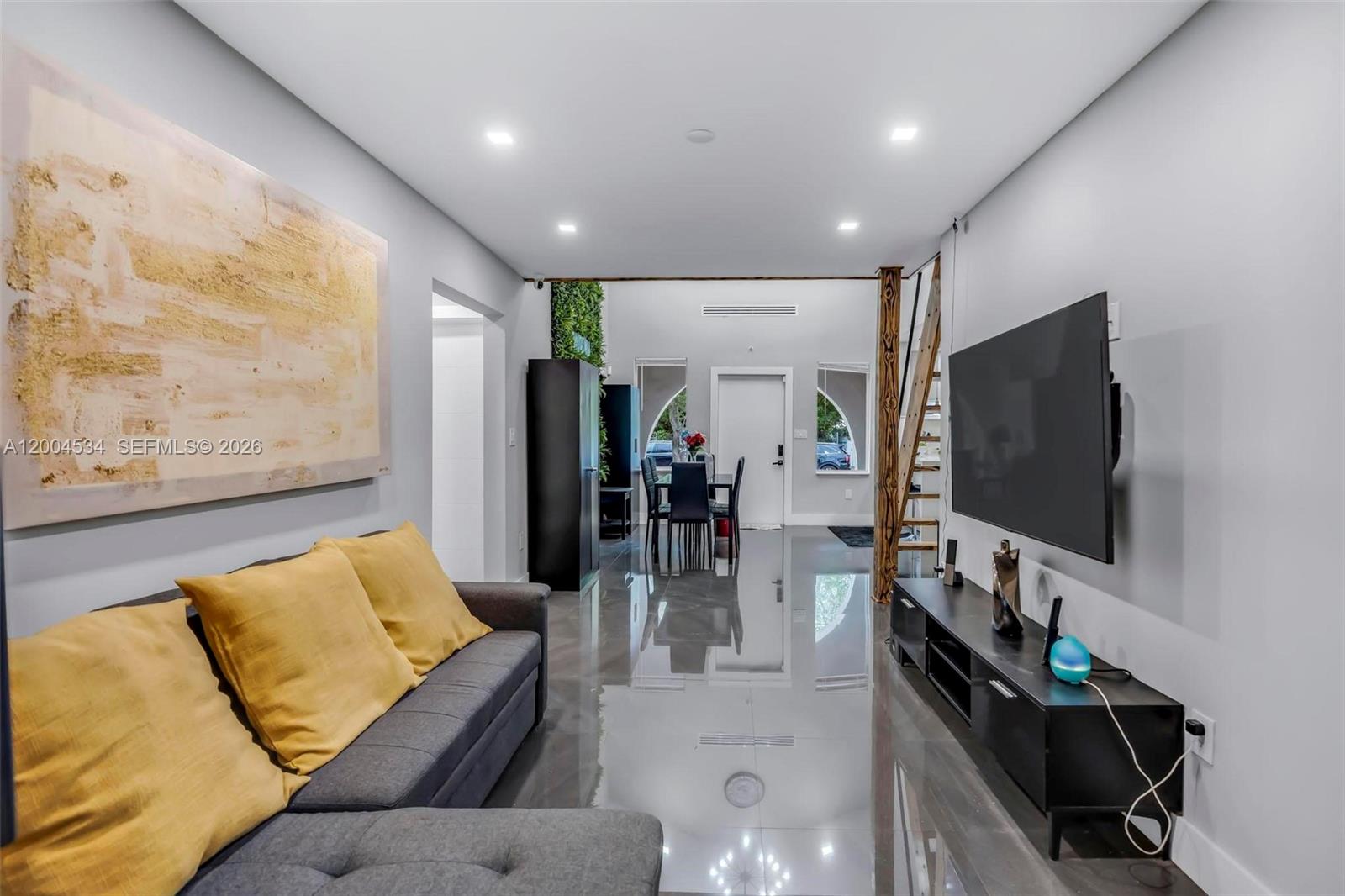 A modern living room features a grey sectional sofa, glossy floors, and a wall-mounted television — 1741 NW 44th St, Miami FL 33142, MIAMI, FL