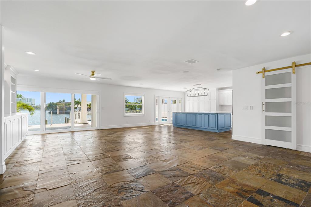 An open-concept living area features slate tile flooring, double glass entry doors, and a barn door — 3924 VERSAILLES DRIVE, TAMPA, FL