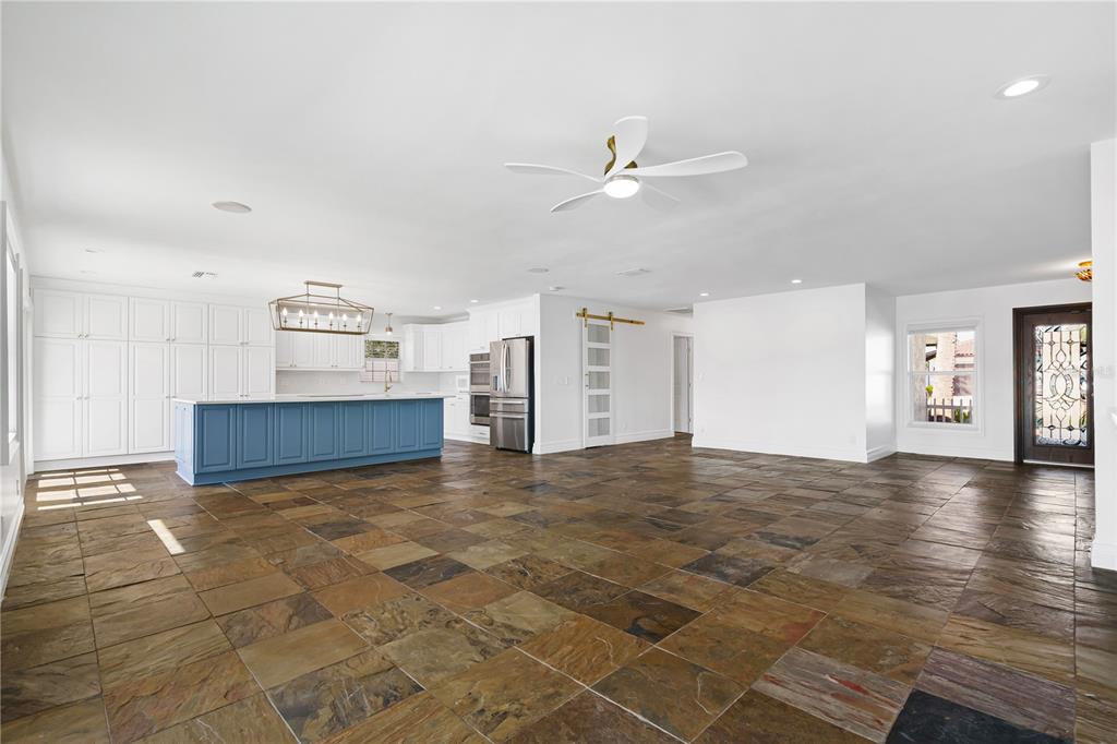 A spacious open-concept room features slate tile flooring, a blue kitchen island, and waterfront views — 3924 VERSAILLES DRIVE, TAMPA, FL