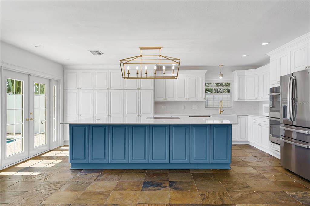A spacious open-concept kitchen and living area features slate tile flooring and a blue island — 3924 VERSAILLES DRIVE, TAMPA, FL