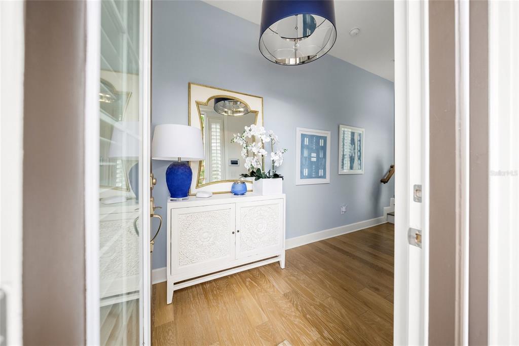 An entryway features a white cabinet, a blue lamp, a mirror, and light wood flooring — 264 SAINT LUCIA DRIVE UNIT 201, BRADENTON, FL