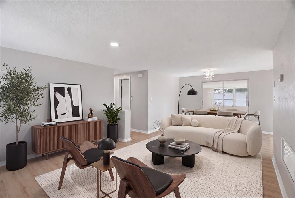 A modern living room features a curved sofa, wooden chairs, and a round coffee table — 3104 SALISBURY DRIVE, HOLIDAY, FL