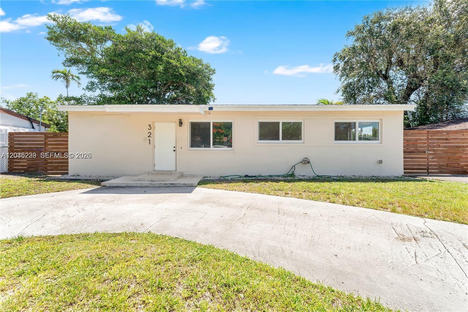 A single-story house with a beige exterior, white door, and a concrete driveway — 321 NW 56th Ave, Miami FL 33126, MIAMI, FL