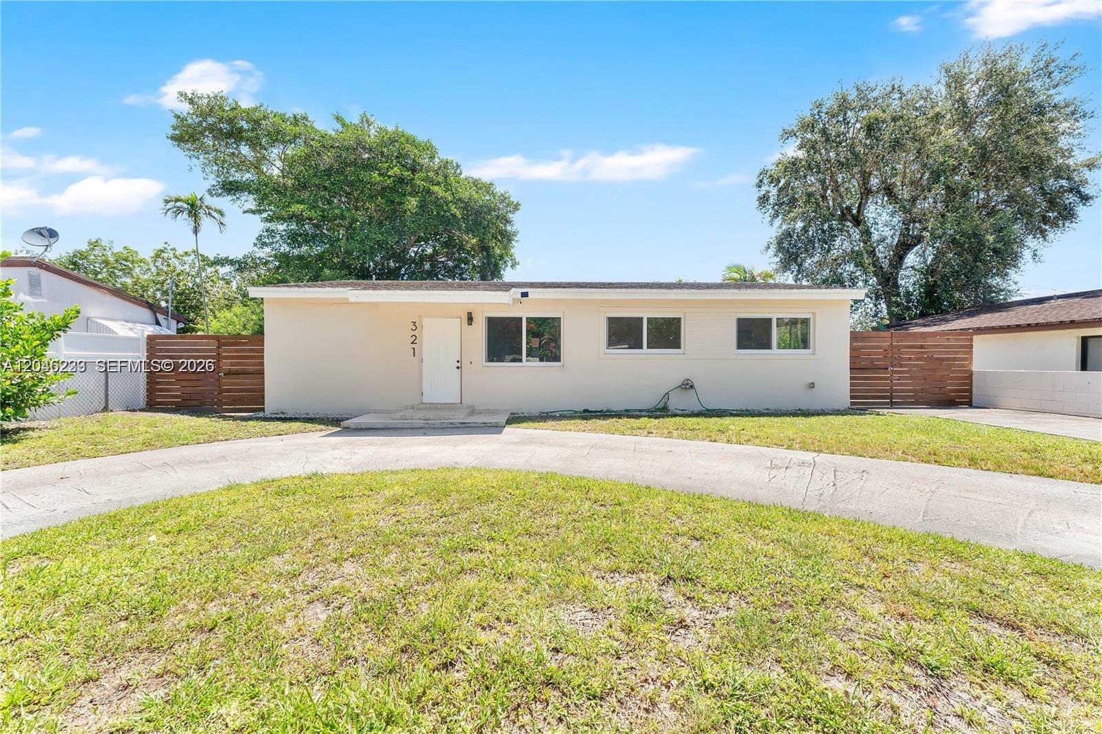A single-story house with a beige exterior, a white front door, and a concrete driveway — 321 NW 56th Ave, Miami FL 33126, MIAMI, FL