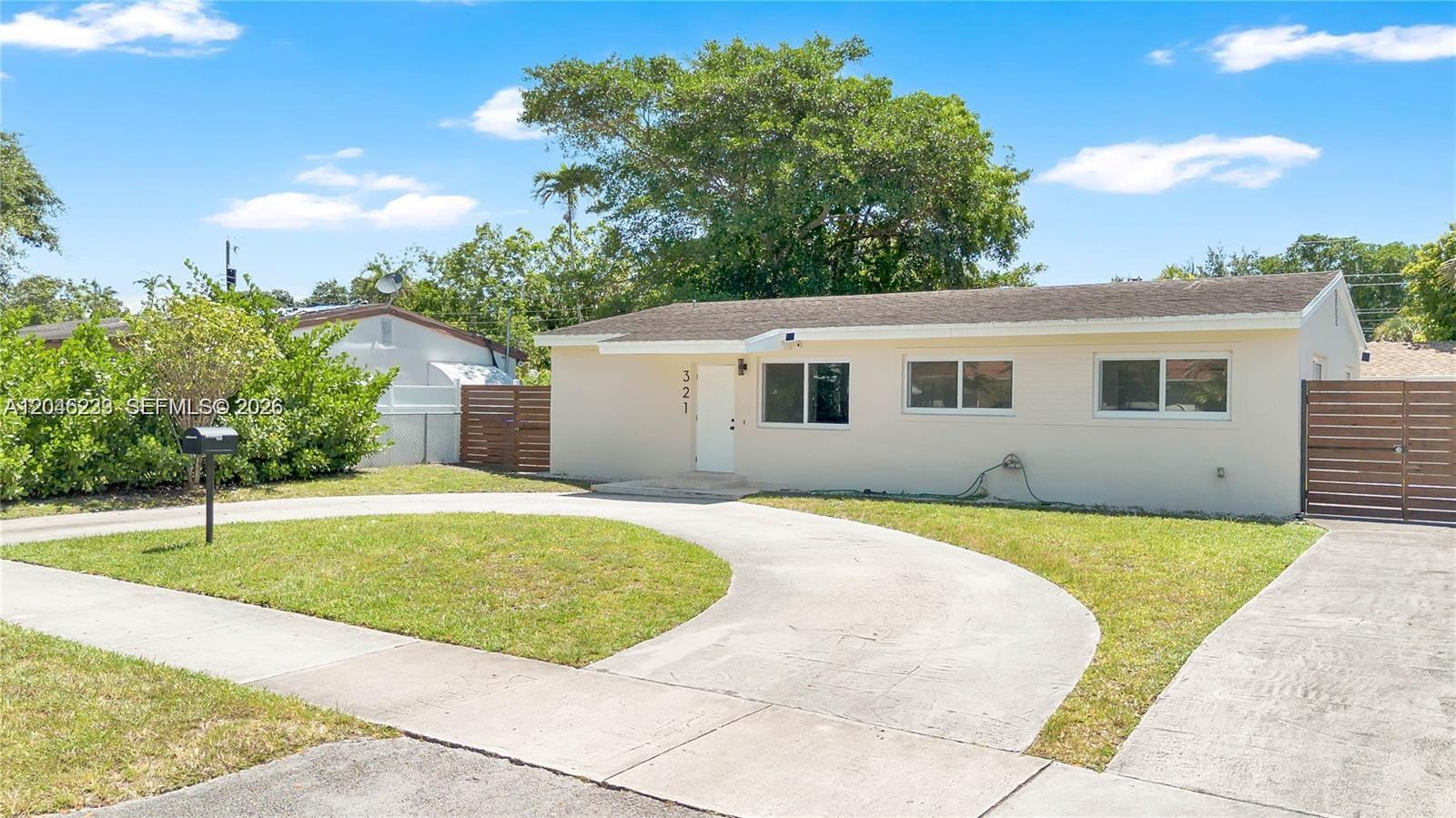 A single-story house with a beige exterior, a curved driveway, and a wooden side fence — 321 NW 56th Ave, Miami FL 33126, MIAMI, FL