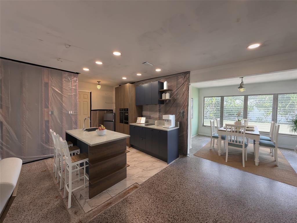 A kitchen with dark blue cabinets and a wood-toned island sits beside a dining area — 414 86TH AVENUE, ST PETE BEACH, FL