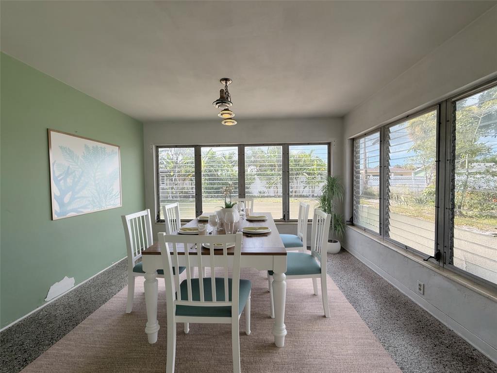 A dining room features a wooden table, white chairs, green accent wall, and large windows — 414 86TH AVENUE, ST PETE BEACH, FL