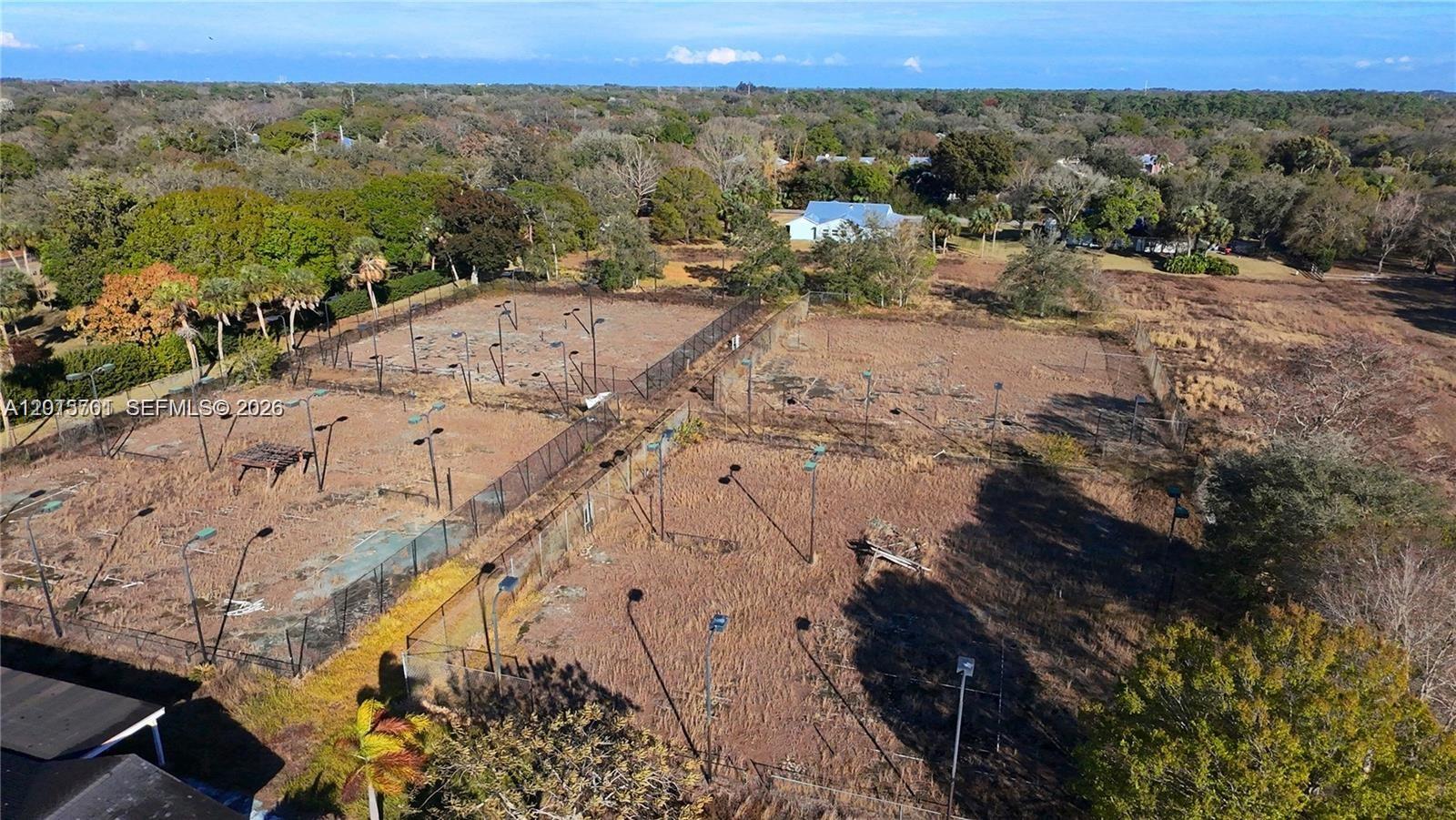 An aerial view shows several abandoned, overgrown tennis courts enclosed by chain-link fencing — 4291 SW 5th Pl SW, Vero Beach FL 32968, VERO BEACH, FL