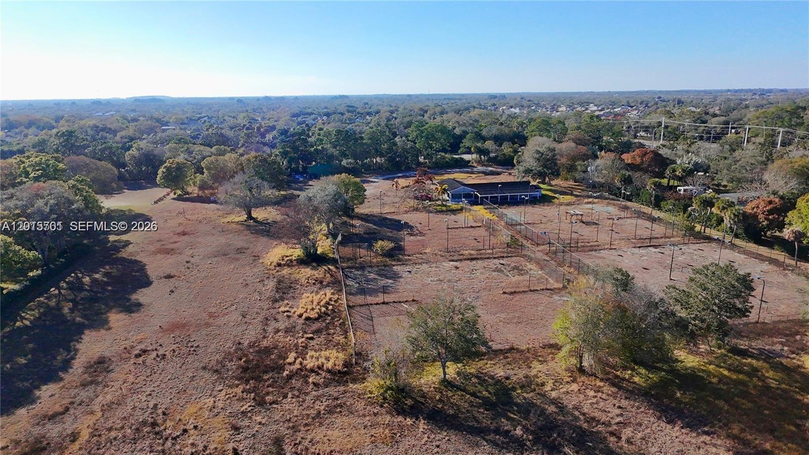 An aerial view shows a large, dry field with several fenced-in tennis courts and a building — 4291 SW 5th Pl SW, Vero Beach FL 32968, VERO BEACH, FL