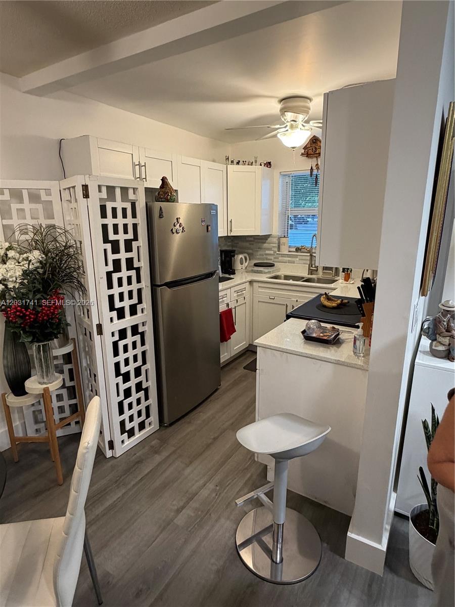 A small kitchen features white cabinets, stainless steel appliances, and a breakfast bar — 3500 Harrison # 4, Hollywood FL 33021, HOLLYWOOD, FL