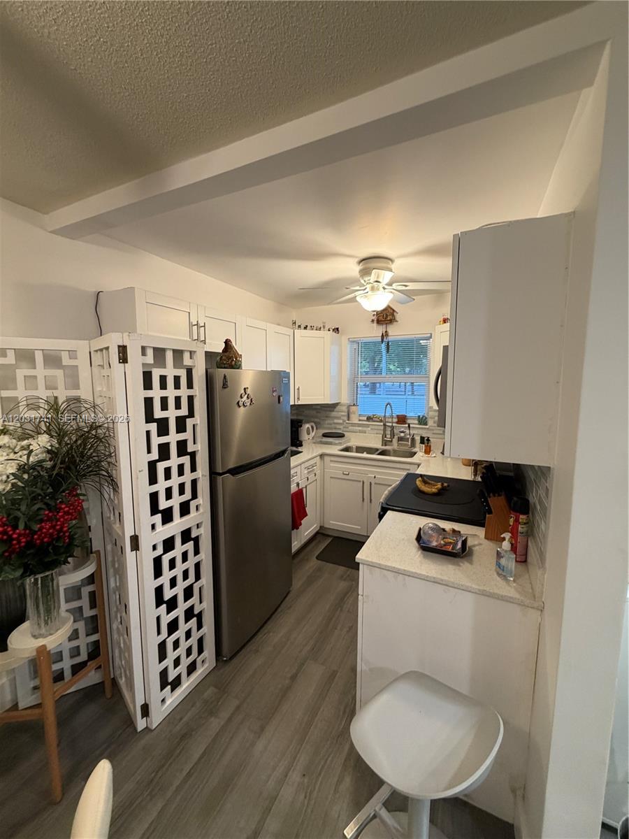A galley-style kitchen features white cabinets, stainless steel appliances, and light gray wood-look flooring — 3500 Harrison # 4, Hollywood FL 33021, HOLLYWOOD, FL