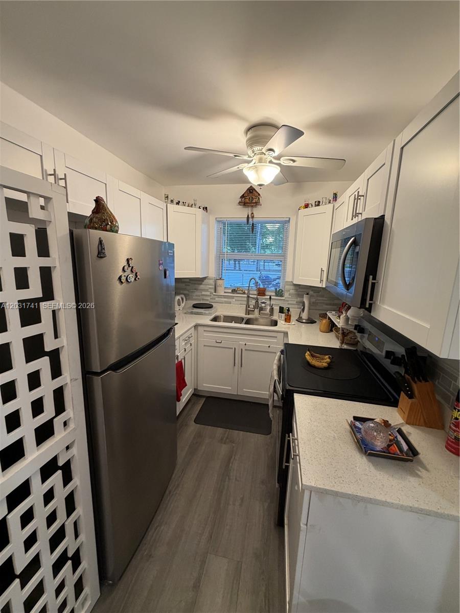 A galley kitchen features white cabinets, stainless steel appliances, and light-colored countertops — 3500 Harrison # 4, Hollywood FL 33021, HOLLYWOOD, FL