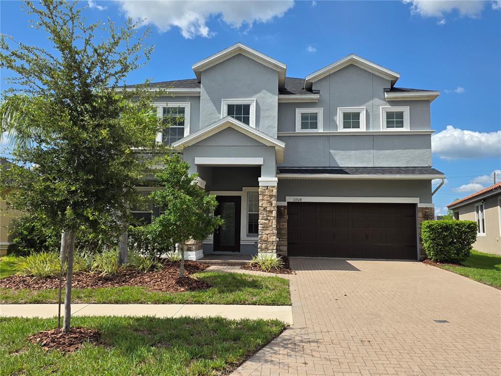 A two-story gray house with a stone-accented entryway and a two-car garage — 11928 FROST ASTER DRIVE, RIVERVIEW, FL