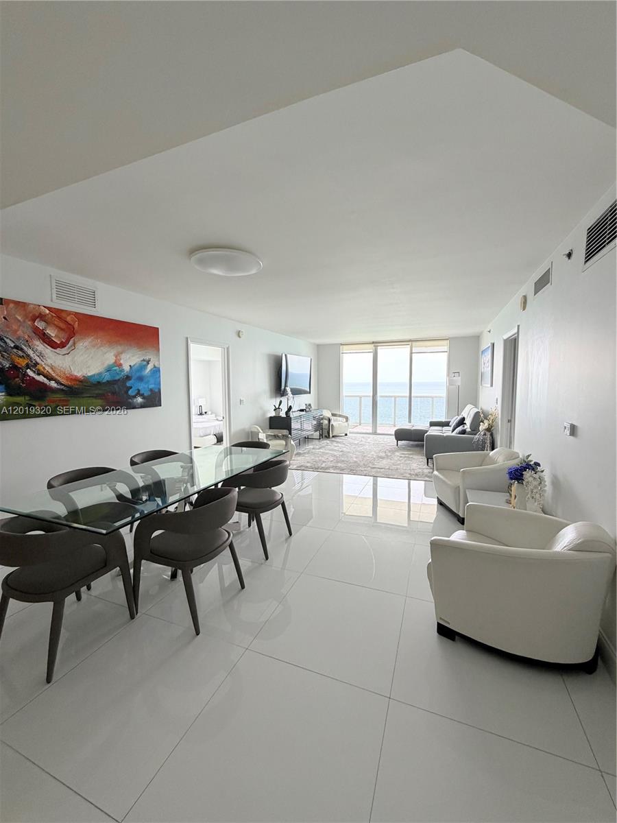 A bright, open-concept living and dining area features white tile floors and ocean views — 1800 S Ocean Dr # 3002, Hallandale Beach FL 33009, HALLANDALE BEACH, FL