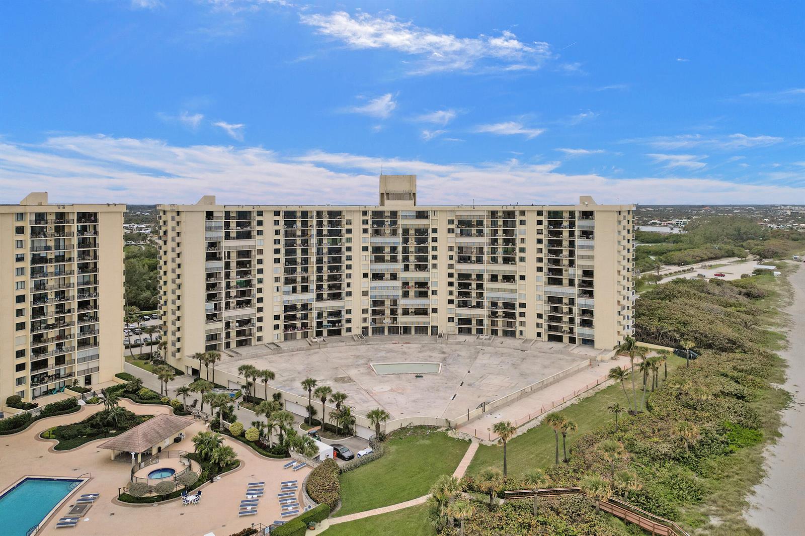 An aerial view of a large tan apartment building with a central concrete courtyard — 400 Ocean Trail Way # 308, Jupiter FL 33477, JUPITER, FL