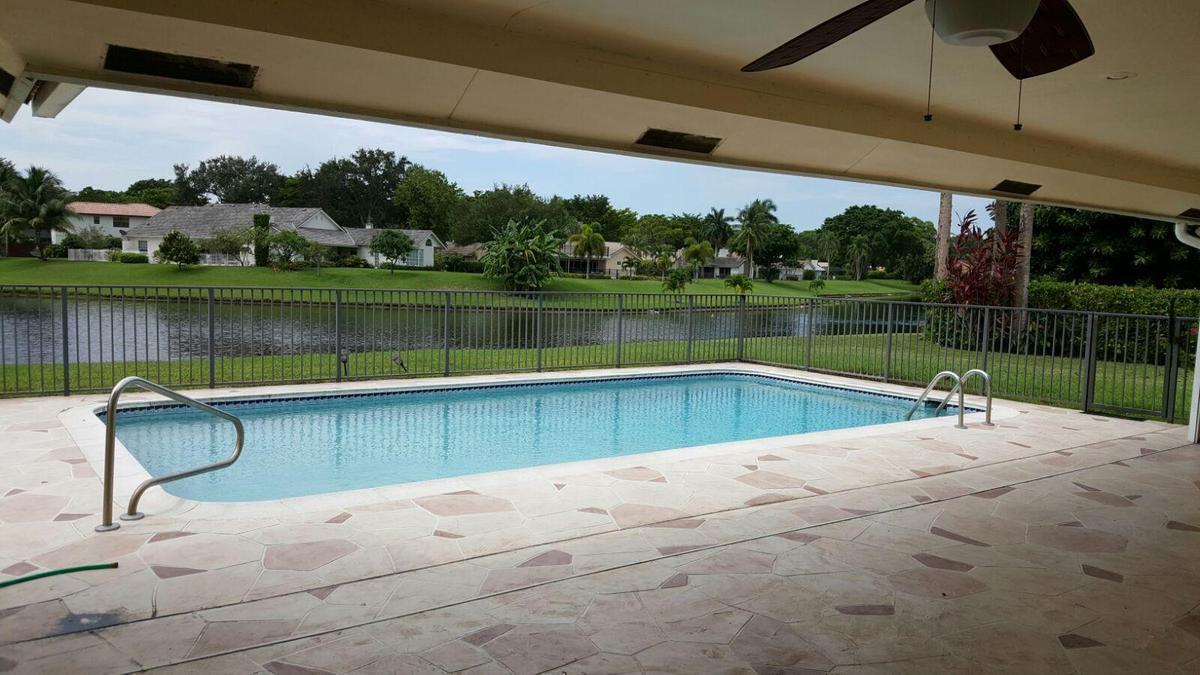 A swimming pool sits on a patio overlooking a lake and a residential neighborhood — 4020 NW 24th Ter Terrace, Boca Raton FL 33431, BOCA RATON, FL