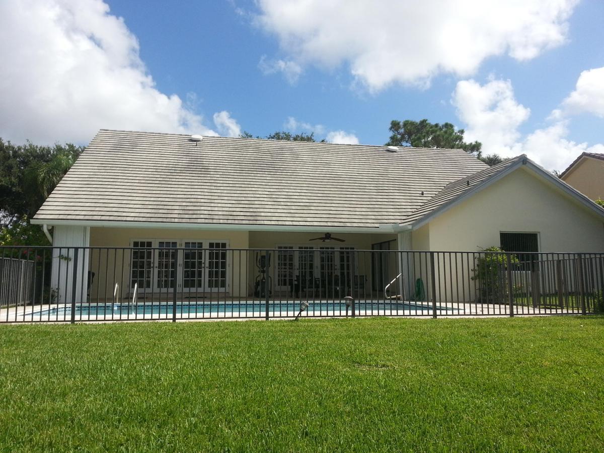 A backyard view of a house with a swimming pool enclosed by a metal fence — 4020 NW 24th Ter Terrace, Boca Raton FL 33431, BOCA RATON, FL