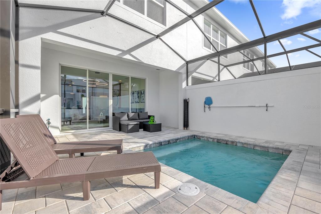 A screened-in patio features a small plunge pool, lounge chairs, and a seating area — 1389 PEACEFUL NATURE WAY, CLERMONT, FL