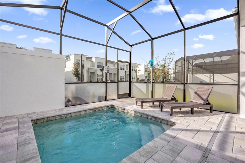 A small swimming pool sits on a paved patio enclosed by a screened-in lanai — 1389 PEACEFUL NATURE WAY, CLERMONT, FL