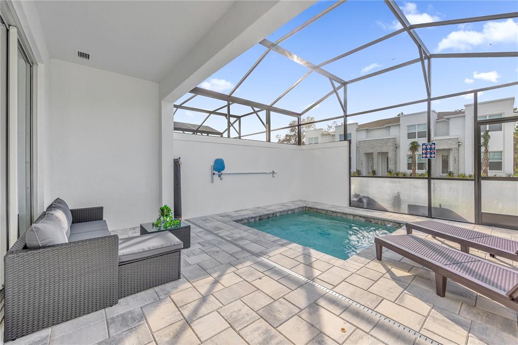 A covered patio features a small plunge pool, lounge furniture, and a screened-in enclosure — 1389 PEACEFUL NATURE WAY, CLERMONT, FL