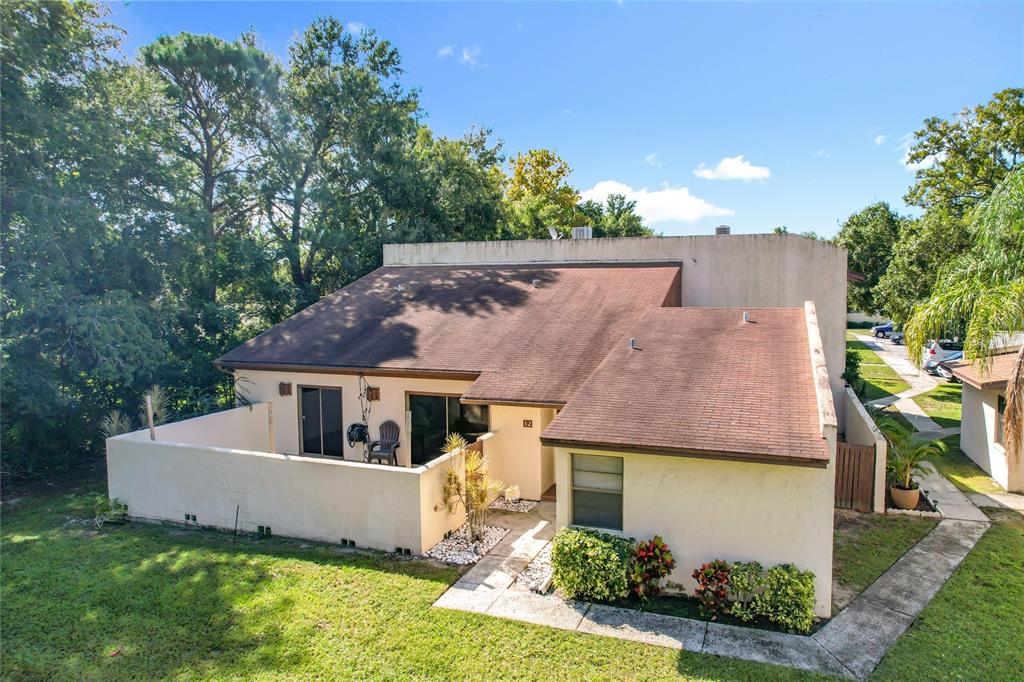 An exterior view of a single-story residential unit with a private patio and brown roof — 1880 N CRYSTAL LAKE DRIVE UNIT 12, LAKELAND, FL