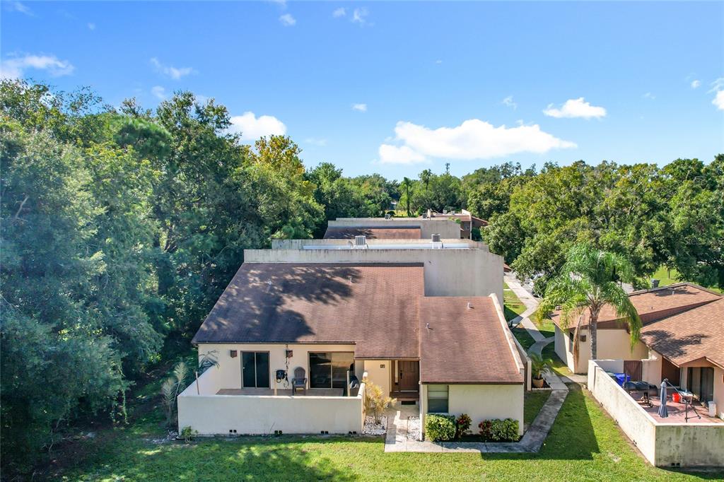 An aerial view shows the rear exterior of a tan townhouse with a brown roof — 1880 N CRYSTAL LAKE DRIVE UNIT 12, LAKELAND, FL