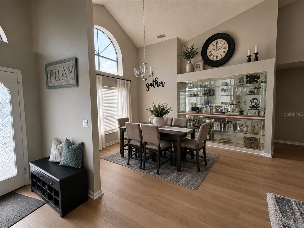 A dining room with a glass-front display cabinet, vaulted ceiling, and a dark wood table — 18561 WINDING OAKS BOULEVARD, HUDSON, FL