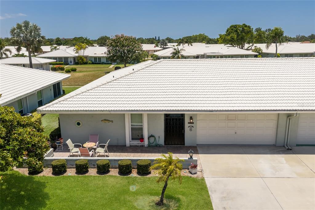 An exterior view of a single-story villa with a white tile roof and patio — 6615 10TH AVENUE W, BRADENTON, FL