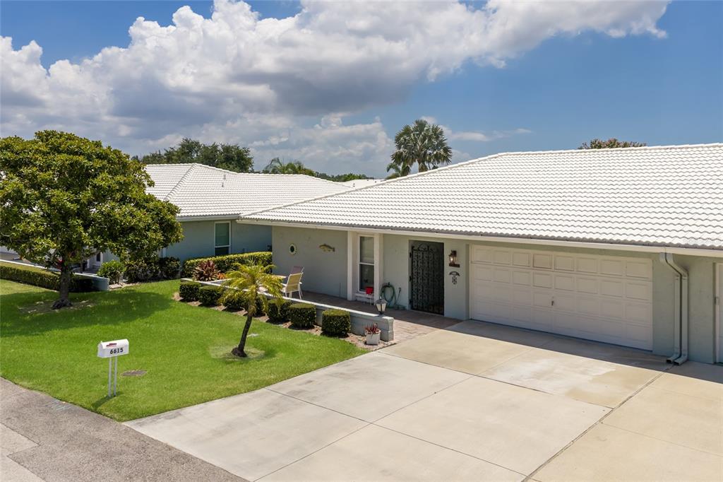 A single-story house with a white tile roof, a two-car garage, and a front lawn — 6615 10TH AVENUE W, BRADENTON, FL