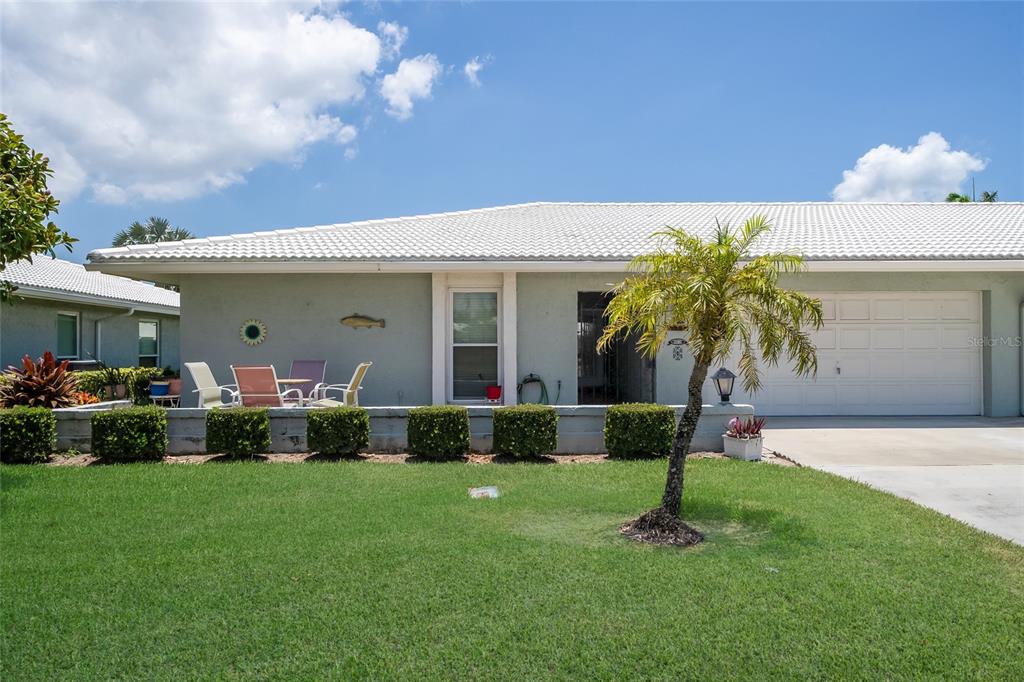 A single-story house with a white tiled roof, light green siding, and a front lawn — 6615 10TH AVENUE W, BRADENTON, FL