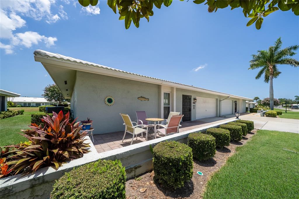 A single-story house exterior features a paved patio, small lawn, and a palm tree — 6615 10TH AVENUE W, BRADENTON, FL