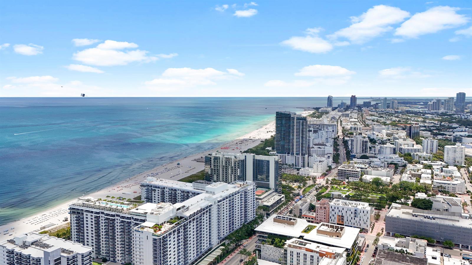 An aerial view shows a coastal city with high-rise buildings along a sandy beach — 8956 Collins Avenue # 4, Surfside FL 33154, SURFSIDE, FL