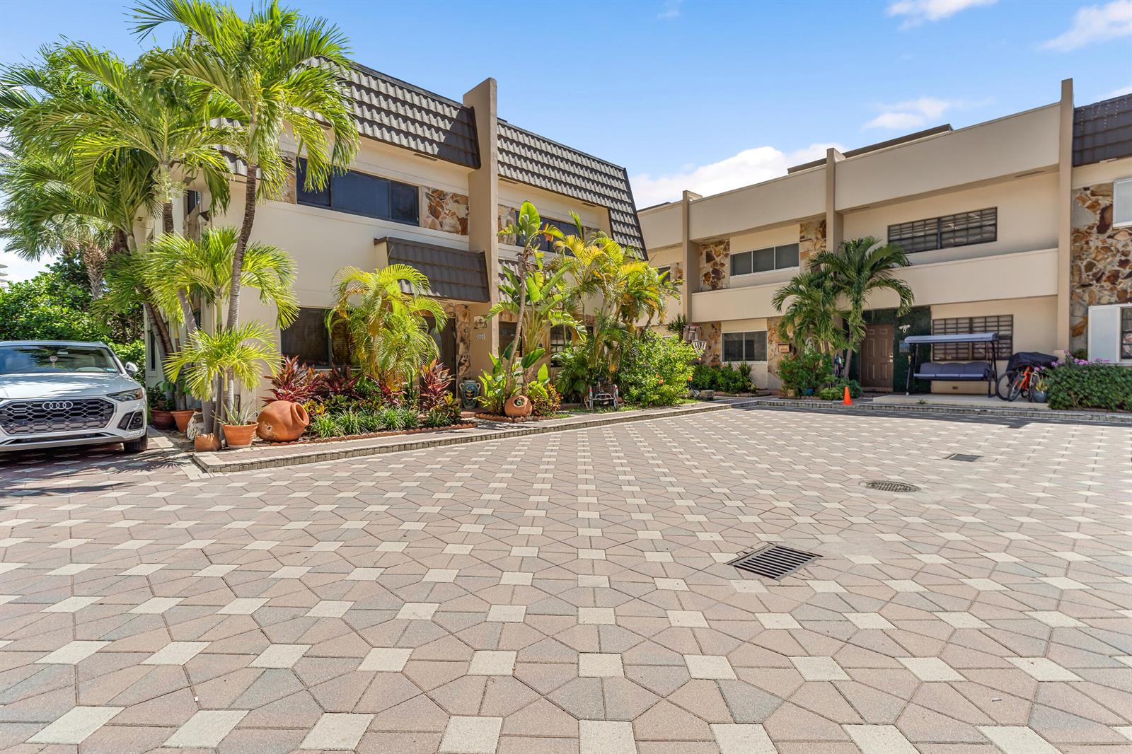 A paved courtyard leads to the entrance of a two-story residential building with palm trees — 8956 Collins Avenue # 4, Surfside FL 33154, SURFSIDE, FL