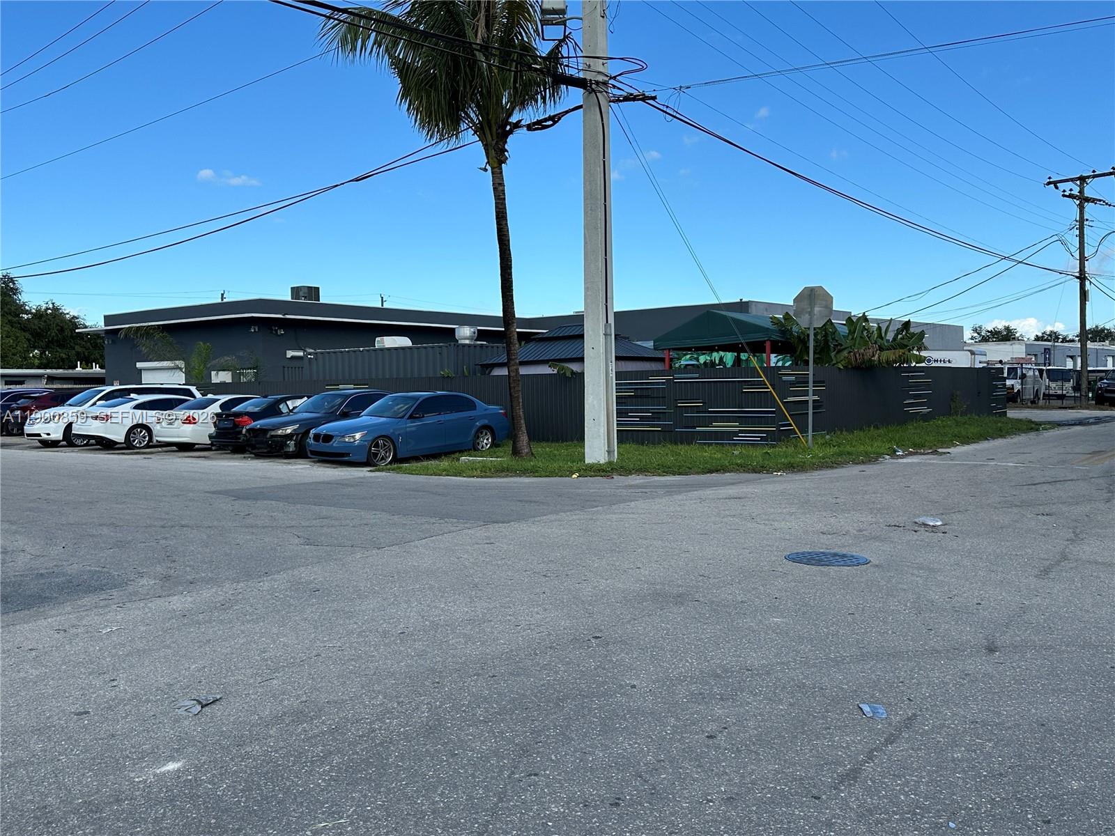 A blue sedan is parked in a lot next to a fenced building and palm tree — 2220 SW 60th Ter, Miramar FL 33023, MIRAMAR, FL