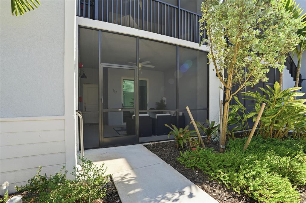 A ground-level patio with a screen enclosure and a concrete walkway leading to the entrance — 14204 HERITAGE LANDING BOULEVARD UNIT 712, PUNTA GORDA, FL