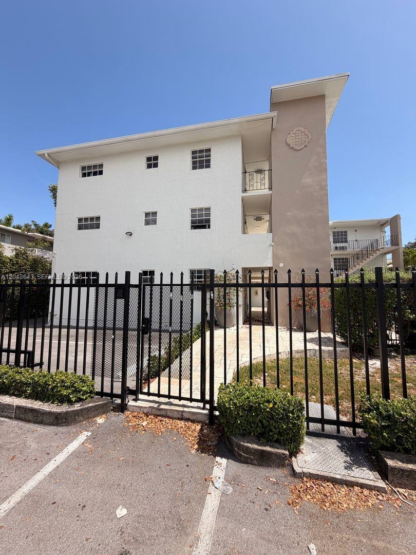 A three-story apartment building exterior features white stucco walls and a gated entrance — 3270 W Trade Ave # 14, Miami FL 33133, MIAMI, FL