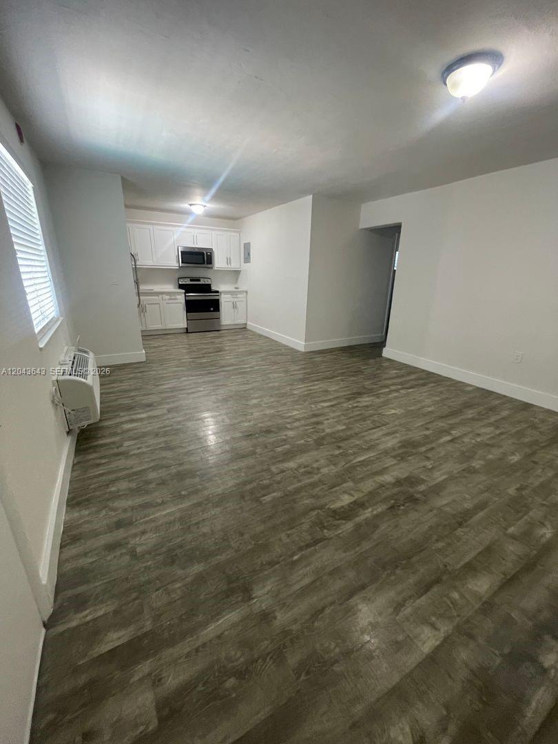 This room features wood-look flooring, white walls, and an open kitchen with white cabinets — 3270 W Trade Ave # 14, Miami FL 33133, MIAMI, FL
