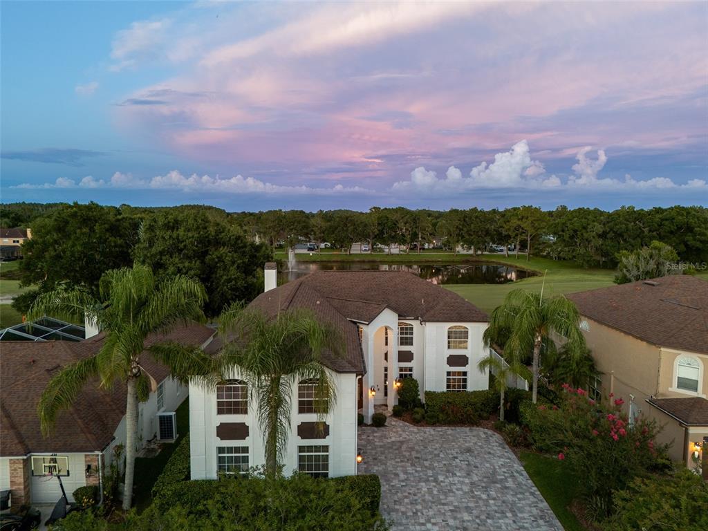An aerial view of a two-story house with a paved driveway and a backyard pond — 15615 SHOAL CREEK PLACE, ODESSA, FL