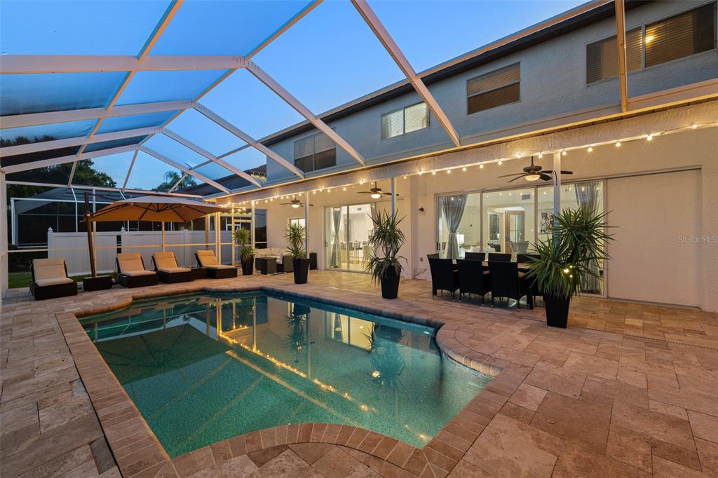 A screened-in patio features a swimming pool, outdoor dining area, and lounge chairs — 15615 SHOAL CREEK PLACE, ODESSA, FL