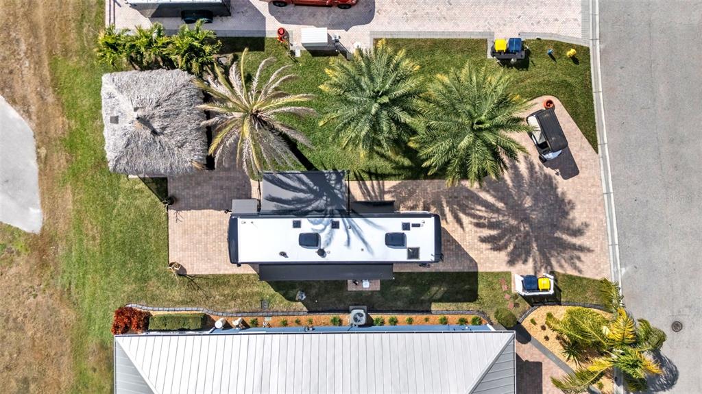 An aerial view shows a recreational vehicle parked on a paved lot with palm trees — 3268 FISH HAWK DRIVE, POLK CITY, FL